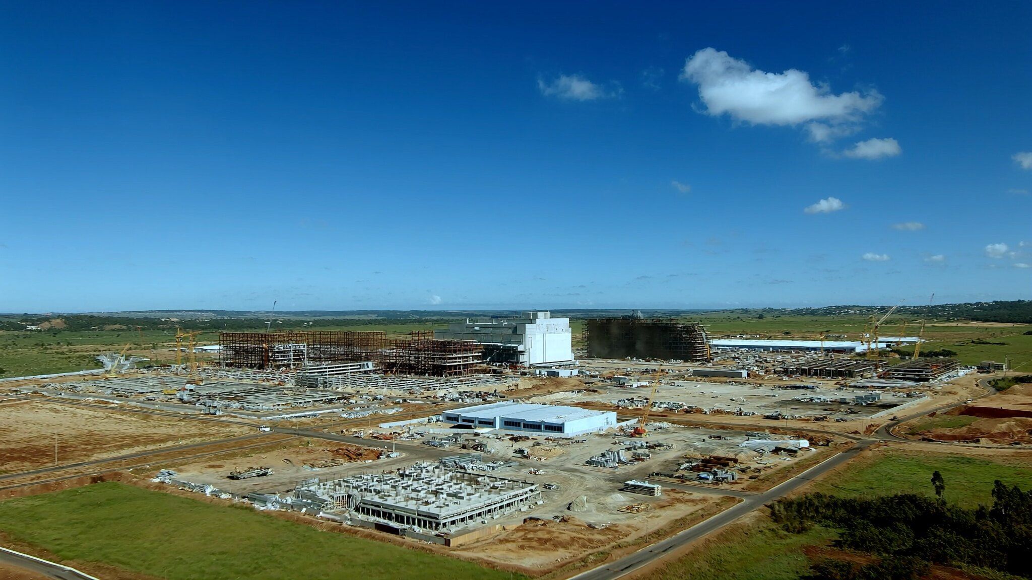 Grande canteiro de obras de uma planta industrial, com fundações e estruturas em montagem, visto do alto